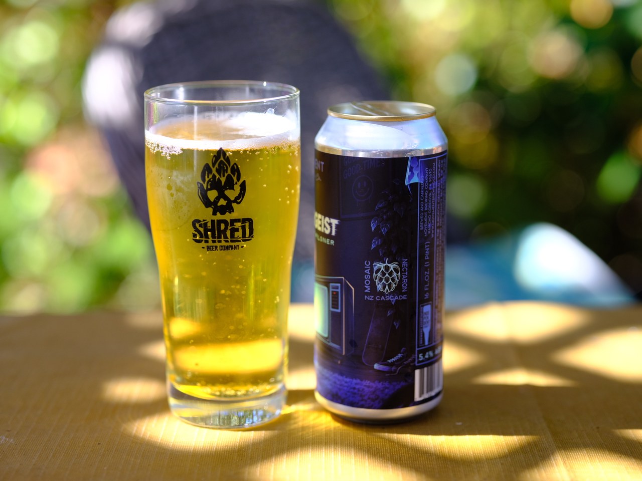 Coldergeist beside a glass, showing the side of the can with its hop list